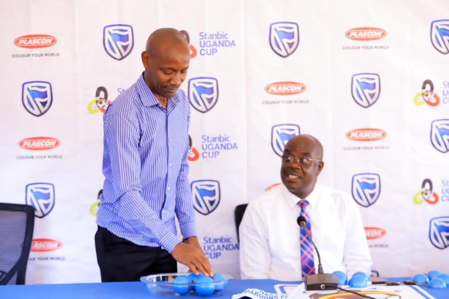 Paul Mukatabala (standing) and Rogers Mulindwa during the Stanbic Uganda Cup Quarterfinal Draw event.